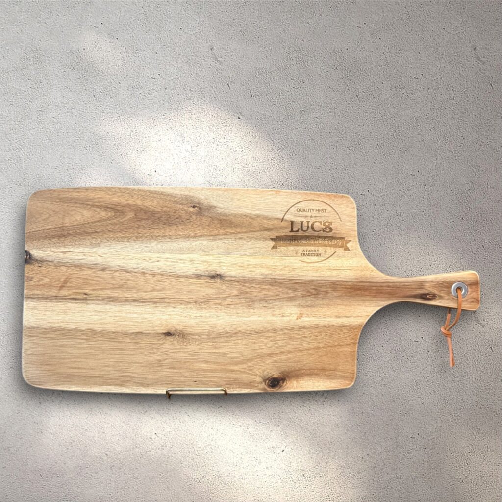 An engraved cutting board showing the logo for "Luc's European Meats"